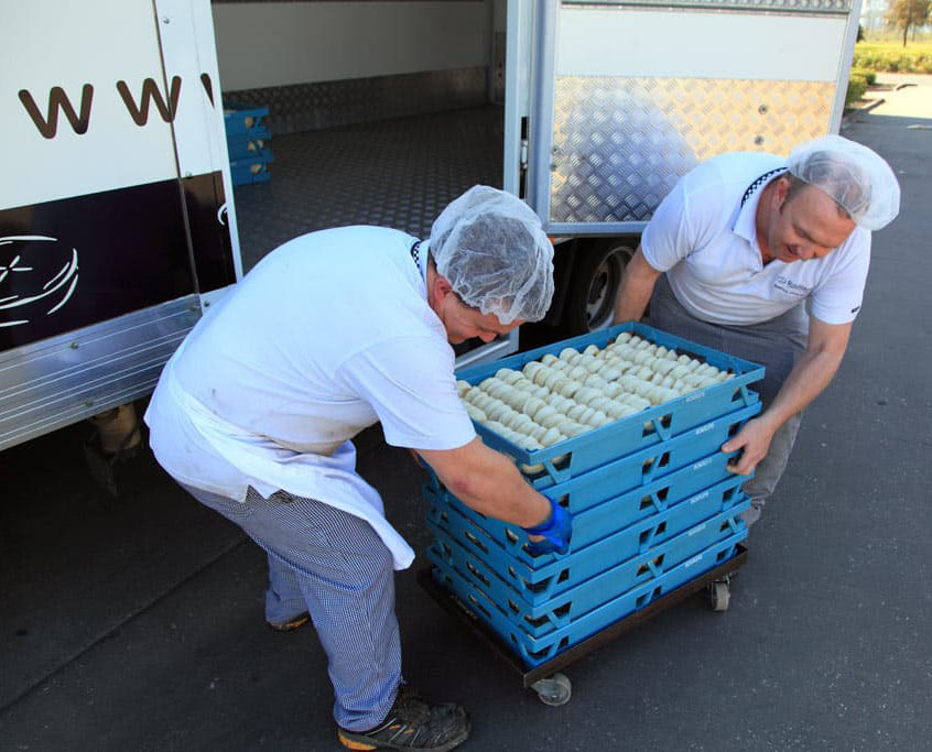 product in Bakers crates stacked on a dolly being loaded onto a truck